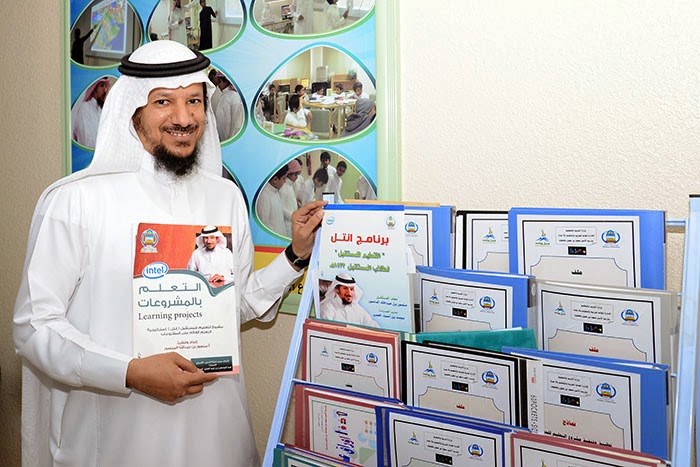 Mansour Al Mansour, vencedor do Global Teacher Prize 2025, sorrindo e segurando uma caneta em sua mesa de trabalho.