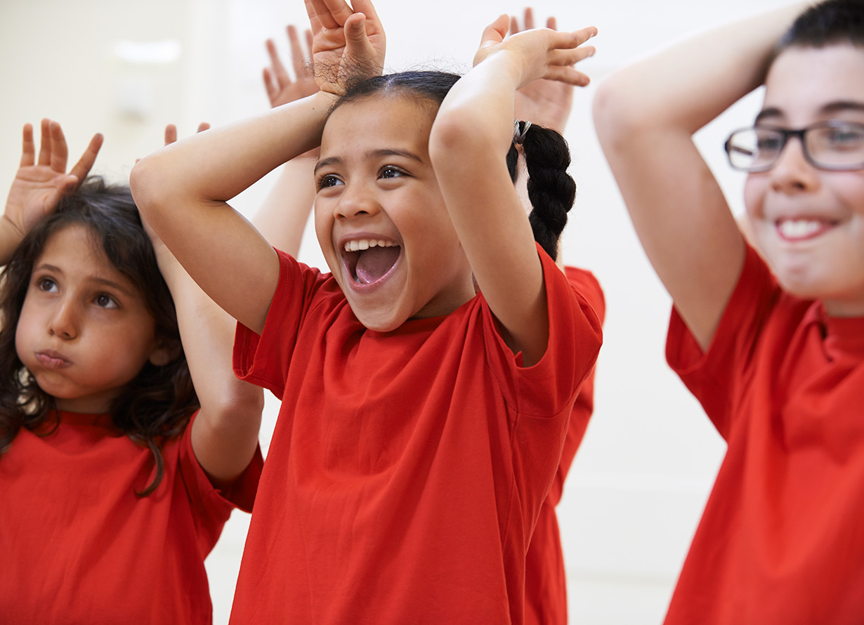 Foto de três crianças com camisetas vermelhas e as mãos para cima, ao lado da cabeça, imitando as orelhas de um coelho (crédito: Highwaystarz-Photography – iStock)